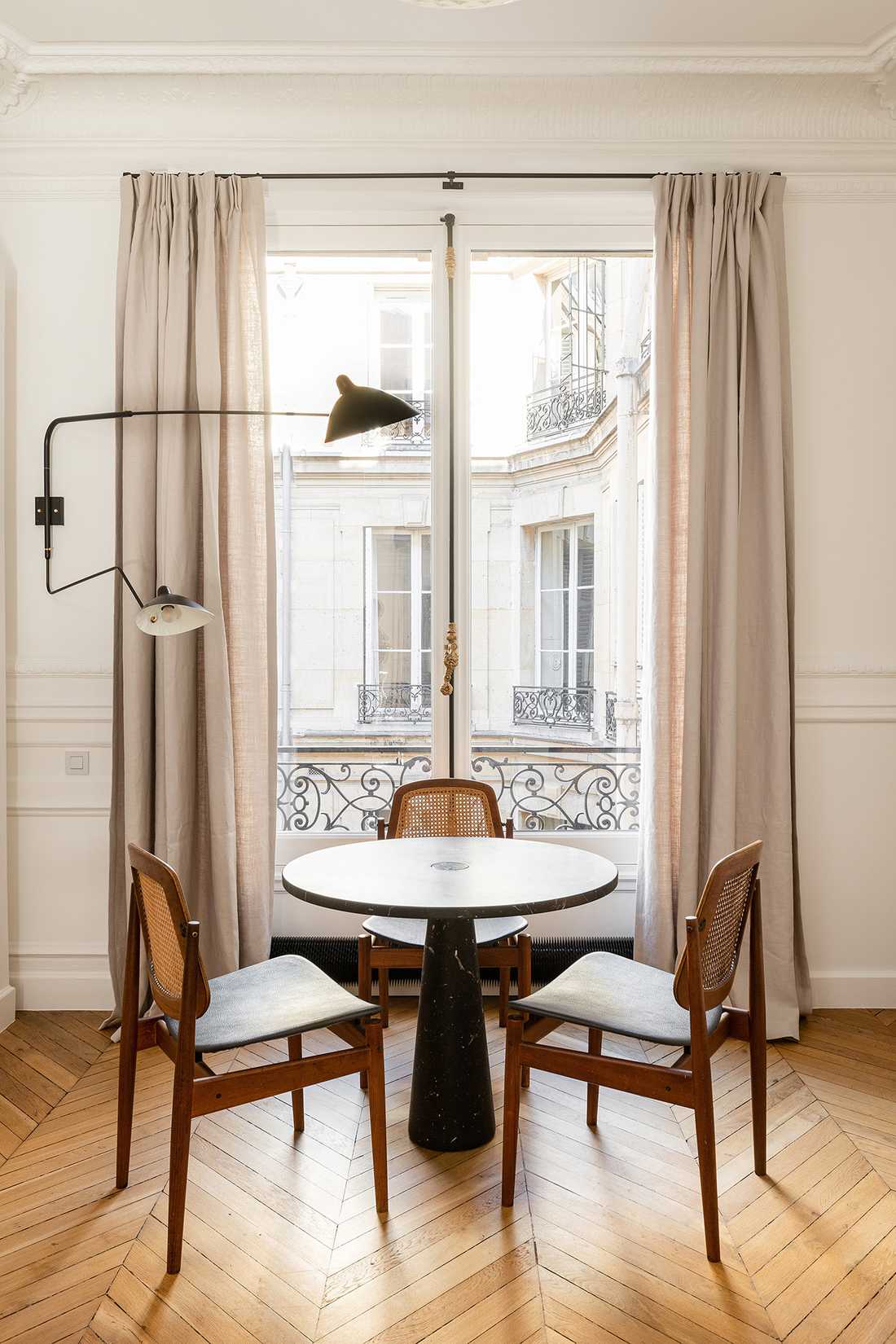 Vue sur la table et ses 3 chaises du salon d'un appartement familial haussmannien